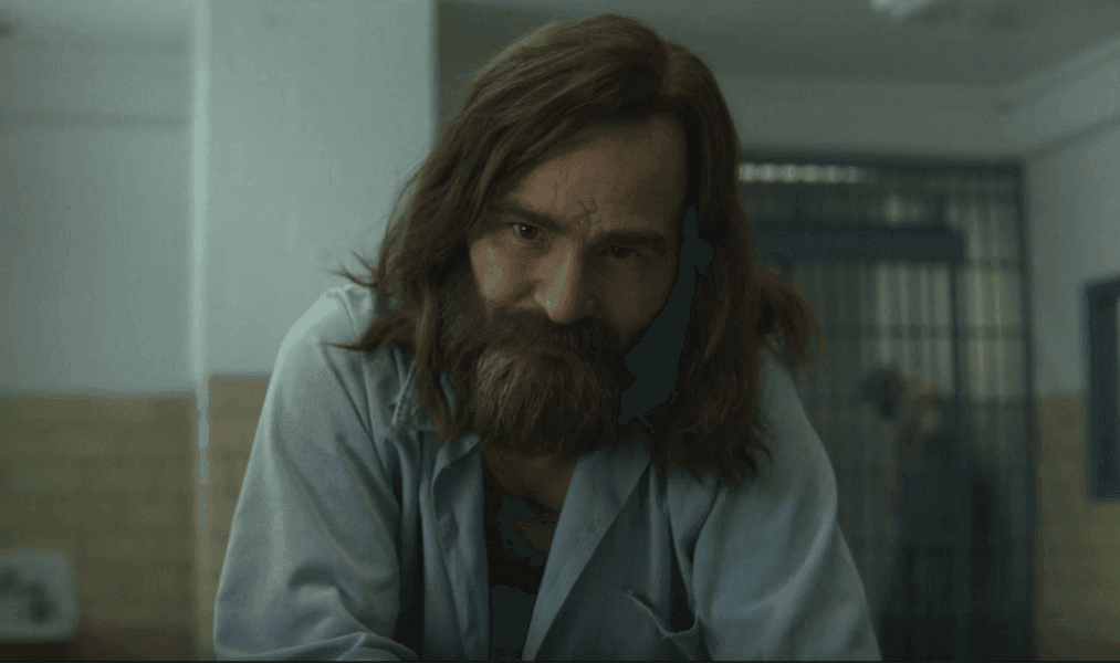 Close-up of a bearded man during a prison interview scene in Mindhunter.